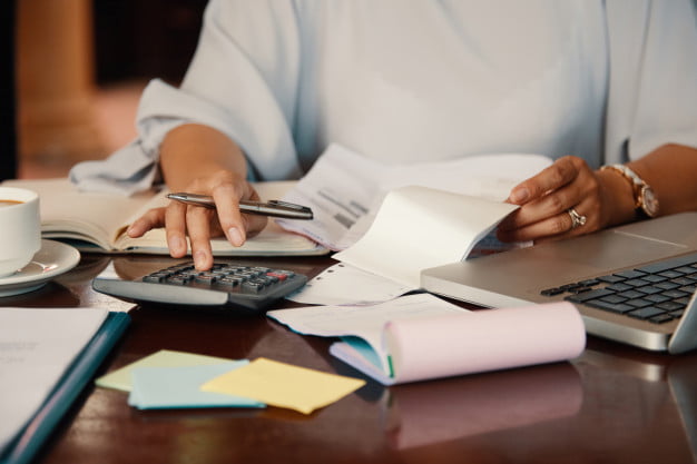 emprendedor-trabajando-facturas_1098-20001 Persona revisa documentos y utiliza una calculadora