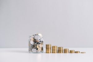 Monedas apiladas y frasco con ahorros