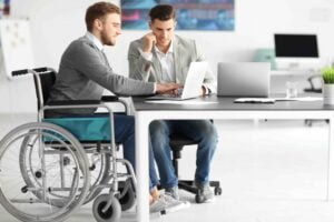 Hombre usuario de silla de ruedas conversa con un compañero de trabajo