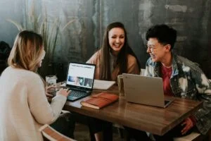 Tres personas trabajan con computadoras en una mesa