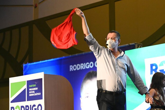 rodrigo chavez 2 Hombre levanta una prenda roja durante un acto público