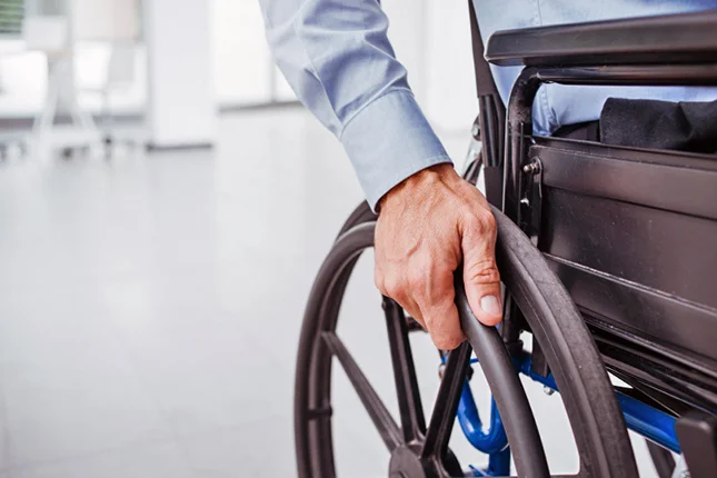 Mano de una persona sobre la rueda de una silla de ruedas