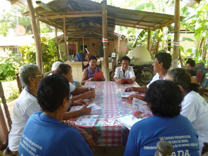 Grupo conversa alrededor de una mesa en un espacio comunitario