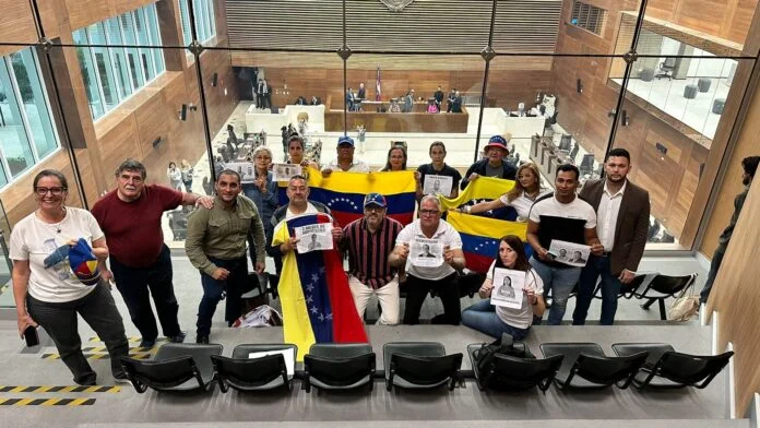 Grupo posa con banderas en una sala institucional