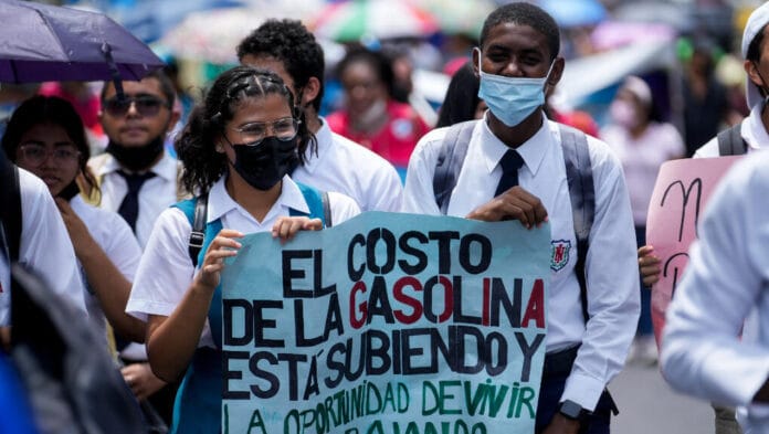 Manifestantes sostienen un cartel sobre el costo de la gasolina