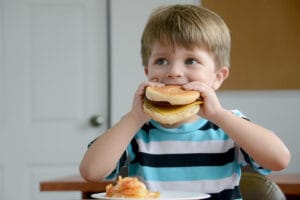 Niño come una hamburguesa