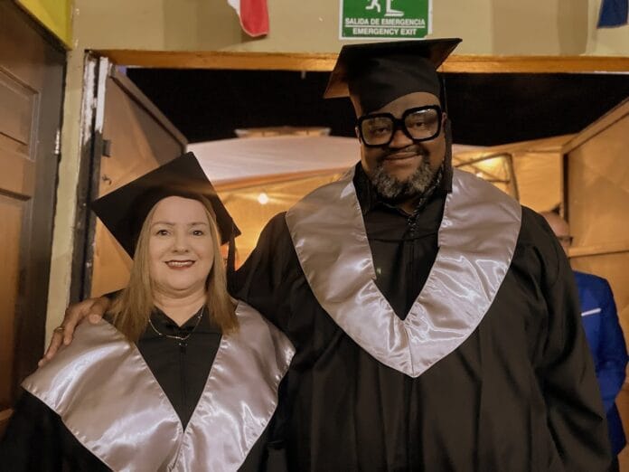 Dos personas posan con vestimenta de graduación